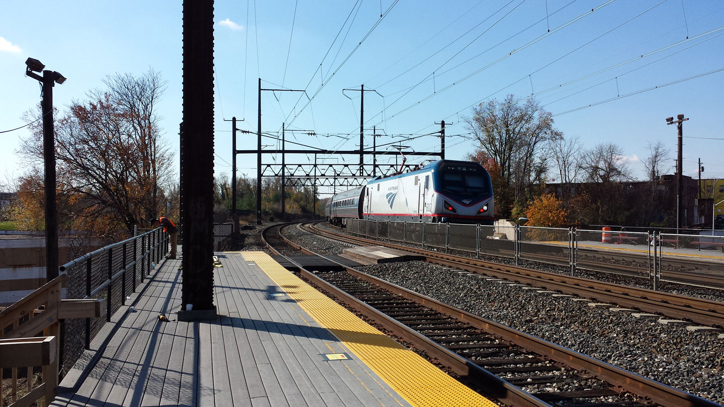 A northbound ACS64 leads a passenger train past the West Baltimore MARC station.